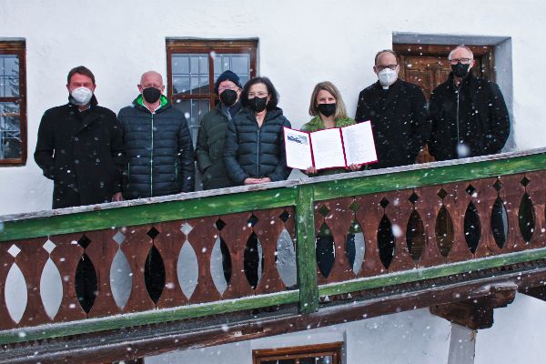 eine Gruppe von Menschen steht auf einem Balkon, eine Frau hält eine Urkunde in Händen