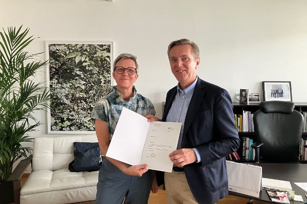 Theresia Niedermüller überreicht Christoph Bazil das Dekret zur Wiederbestellung als Präsident des Bundesdenkmalamtes