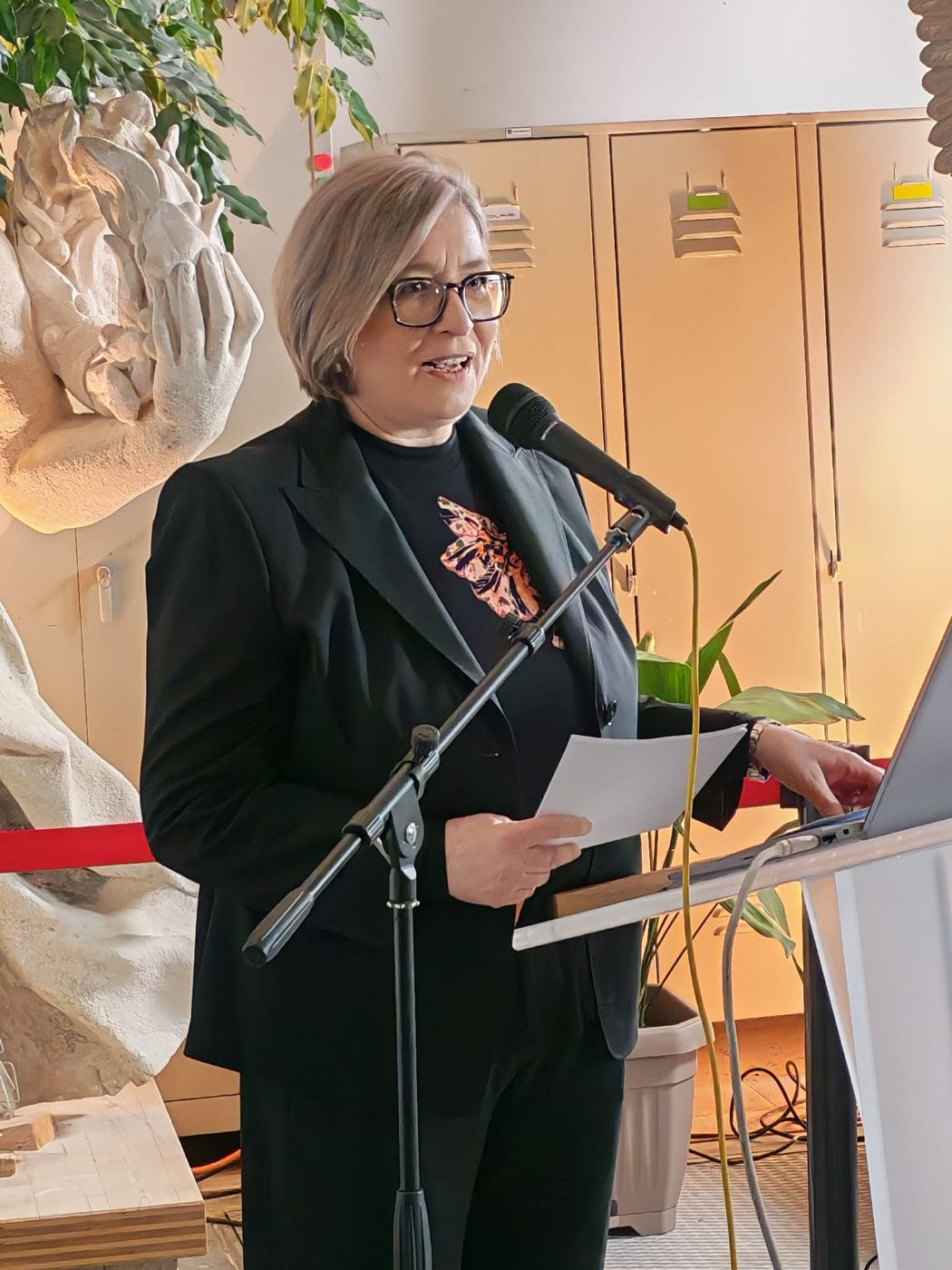 eine Frau steht hinter einem Rednerpult und spricht in ein Mikrofon