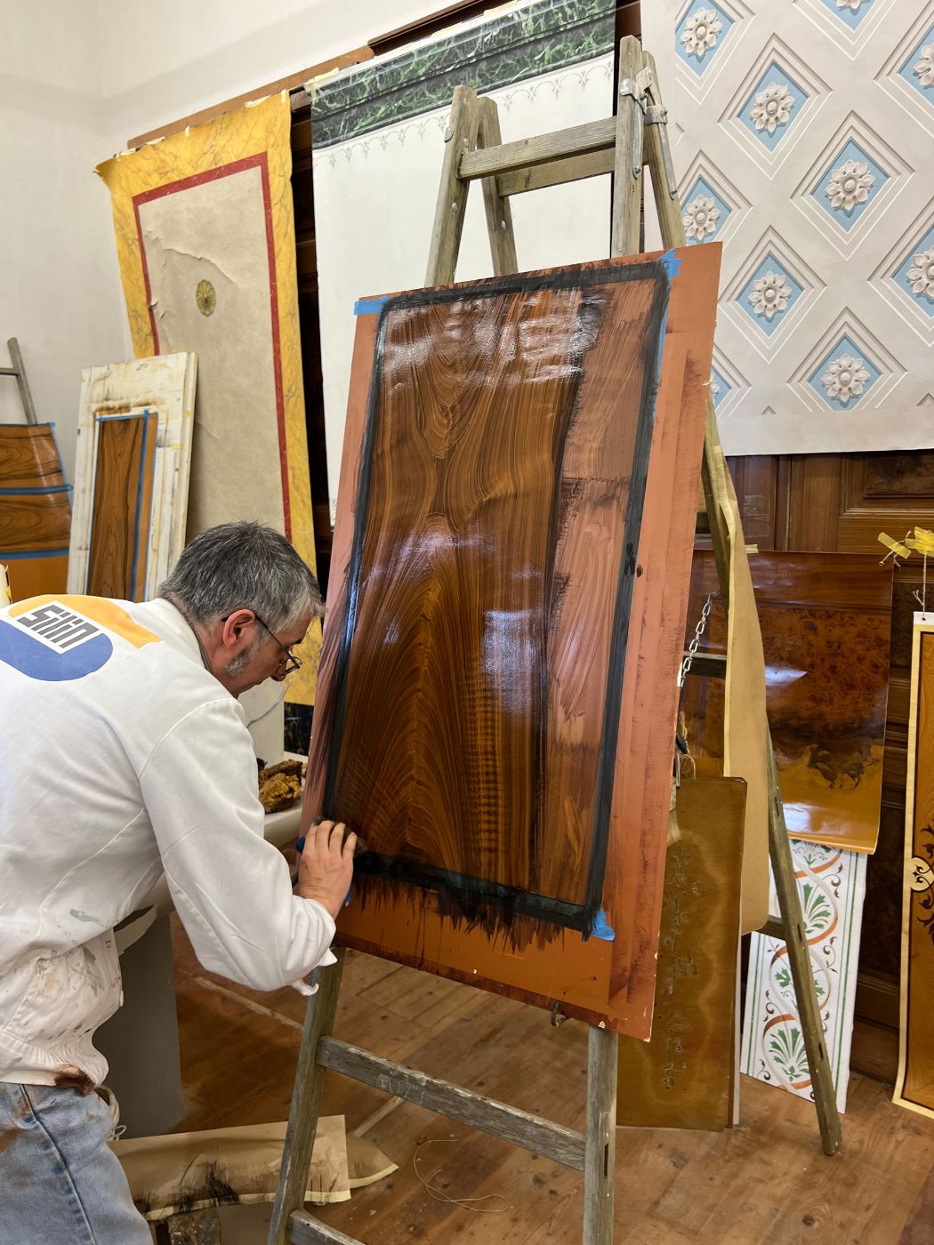 ein Mann malt an einer Staffelei an einem Bild