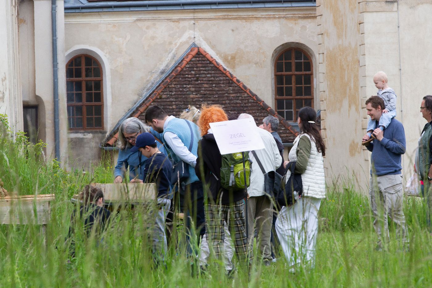 eine Besuchergruppe betrachtet historische Ziegel im Freien in der Kartause Mauerbach