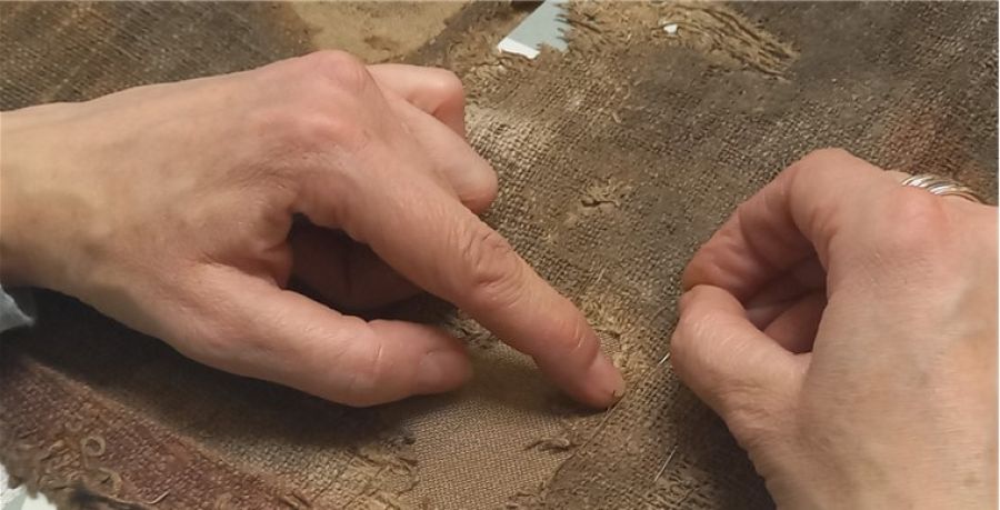 zwei Hände restaurieren das Fastentuch