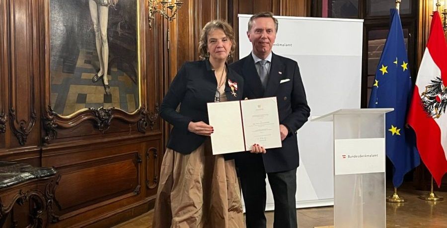 Elena Holzhausen und Christoph Bazil halten gemeinsam die Verleihungsurkunde des Goldenen Ehrenzeichens für Verdienste um die Republik Österreich in die Kamera