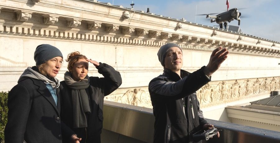 ein Mann lässt auf dem Dach des Parlaments eine Drohnen in die Luft steigen, zwei Frauen sehen dabei zu