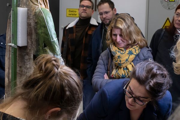 eine Frau erklärt mehreren Personen eine Marienfigur