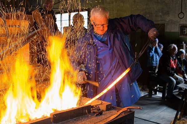 ein Mann schmiedet etwas im Feuer