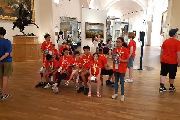 Kinder sitzen auf einer Bank in einem Ausstellungssaal eines Museums
