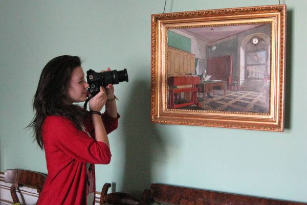 ein Mädchen fotografiert ein Gemälde