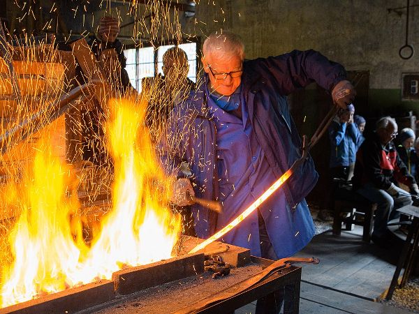 ein Mann schmiedet etwas im Feuer