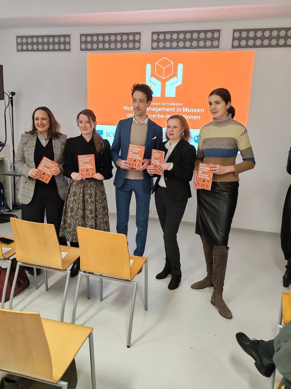 eine Gruppe von Menschen steht in einem Raum und präsentiert gemeinsam eine Publikation