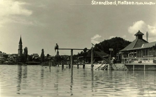Schwarz-Weiß-Foto mit Blick vom Wasser auf den Steg und das Badehaus im Seebad in Mattsee