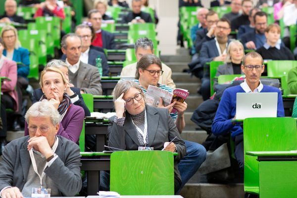 Fachgespräch: Zwischen Alt und Anders, Detail: eine Frau blättert in einem Hörsaal in der Zeitschrift "Denkmal heute"