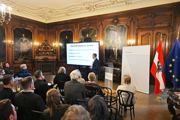 ein Mann steht in einem Vortragssaal und spricht zum Publikum