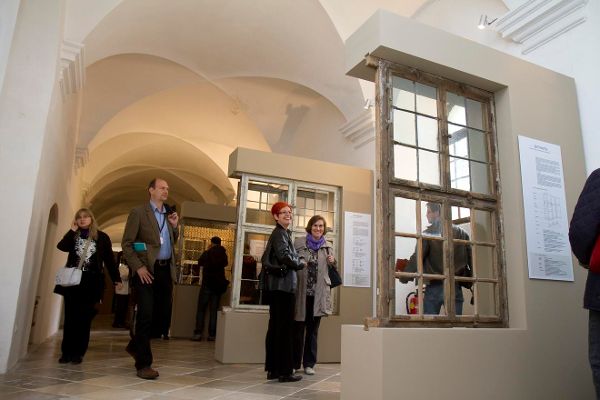 Menschen stehen in einem Ausstellungsraum und betrachten verschiedene Fensterrahmen