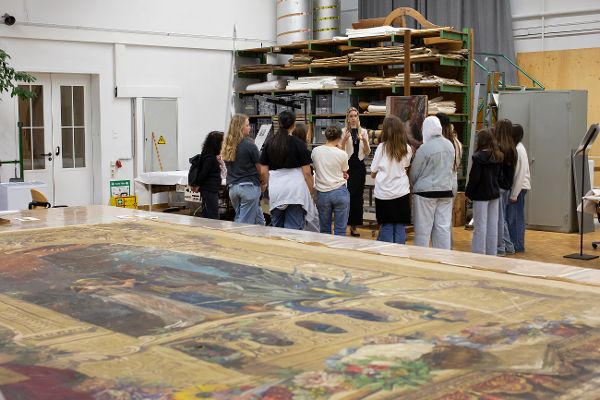 eine Frau erklärt einer Gruppe mit Kindern etwas