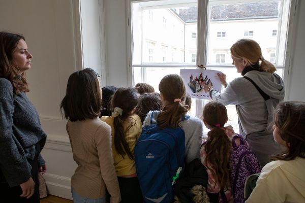 eine Frau zeigt Kindern ein Blatt