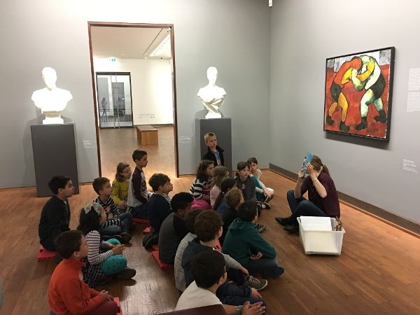 Eine Kindergruppe sitzt am Boden im Museum